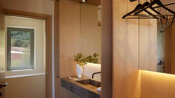 Un baño moderno con tocador de madera, ventana, planta y espejo.