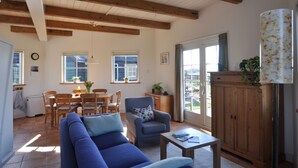 A spacious living room with a blue sofa, a wooden dining table, and a cabinet. - Cottage detached for ref; https://www.vrbo.com/nl-nl/vakantiewoning/p1114020 (Alphen aan den Rijn)