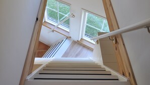 A staircase with wooden handrails and a view of a room with a window and a radiator. - Cottage detached for ref; https://www.vrbo.com/nl-nl/vakantiewoning/p1114020 (Alphen aan den Rijn)