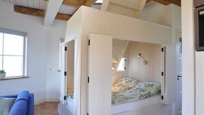 A bedroom with a bunk bed, a window with a view, a blue sofa, and a wooden ceiling. - Cottage detached for ref; https://www.vrbo.com/nl-nl/vakantiewoning/p1114020 (Alphen aan den Rijn)