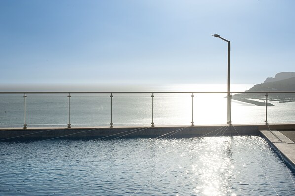 Une piscine offrant une vue sur la mer et sur une étendue de terre lointaine.