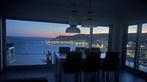 Ett modernt matområde med utsikt över havet och stadens ljus under skymningen.