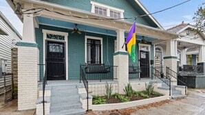 A two-story house with a porch, a flag, and a small garden.