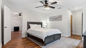 Ein Schlafzimmer mit einem Bett, einem Deckenventilator, einem Gemälde und Holzboden.