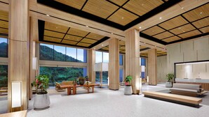 Un vestíbulo amplio con techos altos, ventanas grandes y vistas a un paisaje montañoso.