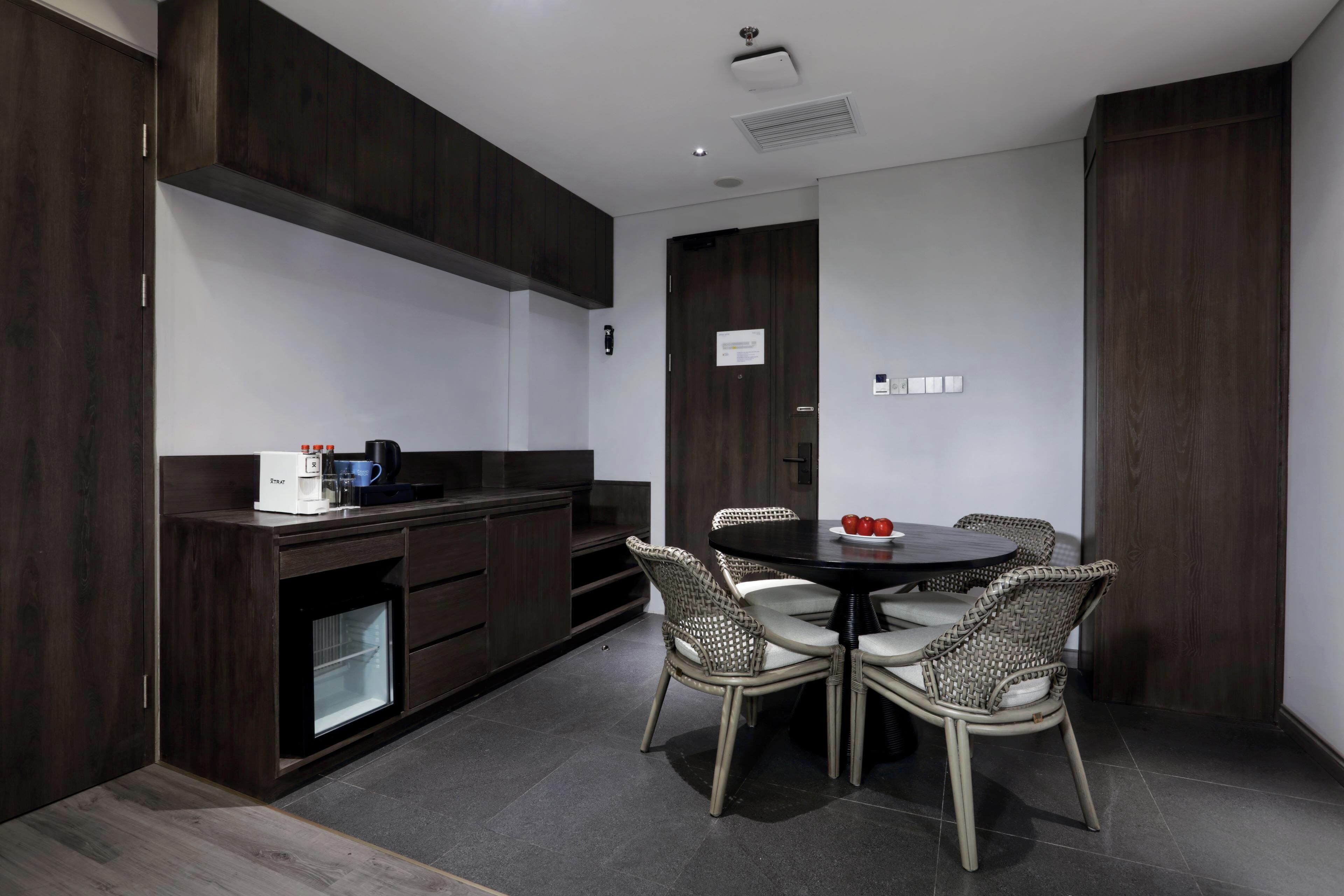 Una cocina moderna con muebles de madera oscura, un refrigerador empotrado y una mesa de comedor redonda con sillas de mimbre.