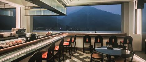 A restaurant with a bar area, chairs, and a table.