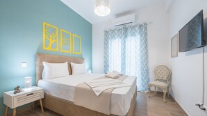 A bedroom with a bed, bedside table, chair, and artwork on the wall. - Easy Living Suite by Cloudkeys (Athens)