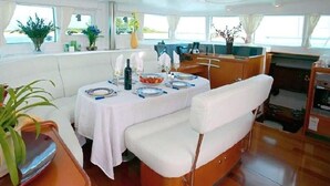 A dining area with a table set for two, a cushioned bench, and a view of the sea through large windows. - Lagoon Ocean (Kuta)
