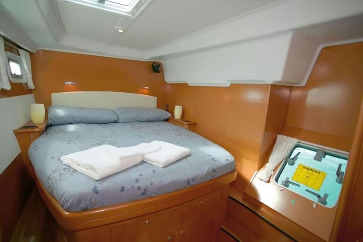A bedroom with a bed, bedside tables, a window with curtains, and a warning sign.