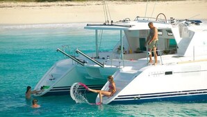 A yacht with a covered deck, a person standing on the bow, and another person sitting on the side. - Lagoon Ocean (Kuta)