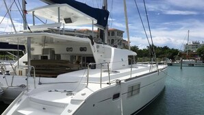 A white yacht docked at a marina with a covered deck area and a cabin. - Lagoon Ocean (Kuta)