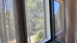 Una ventana con vista a árboles y una valla.