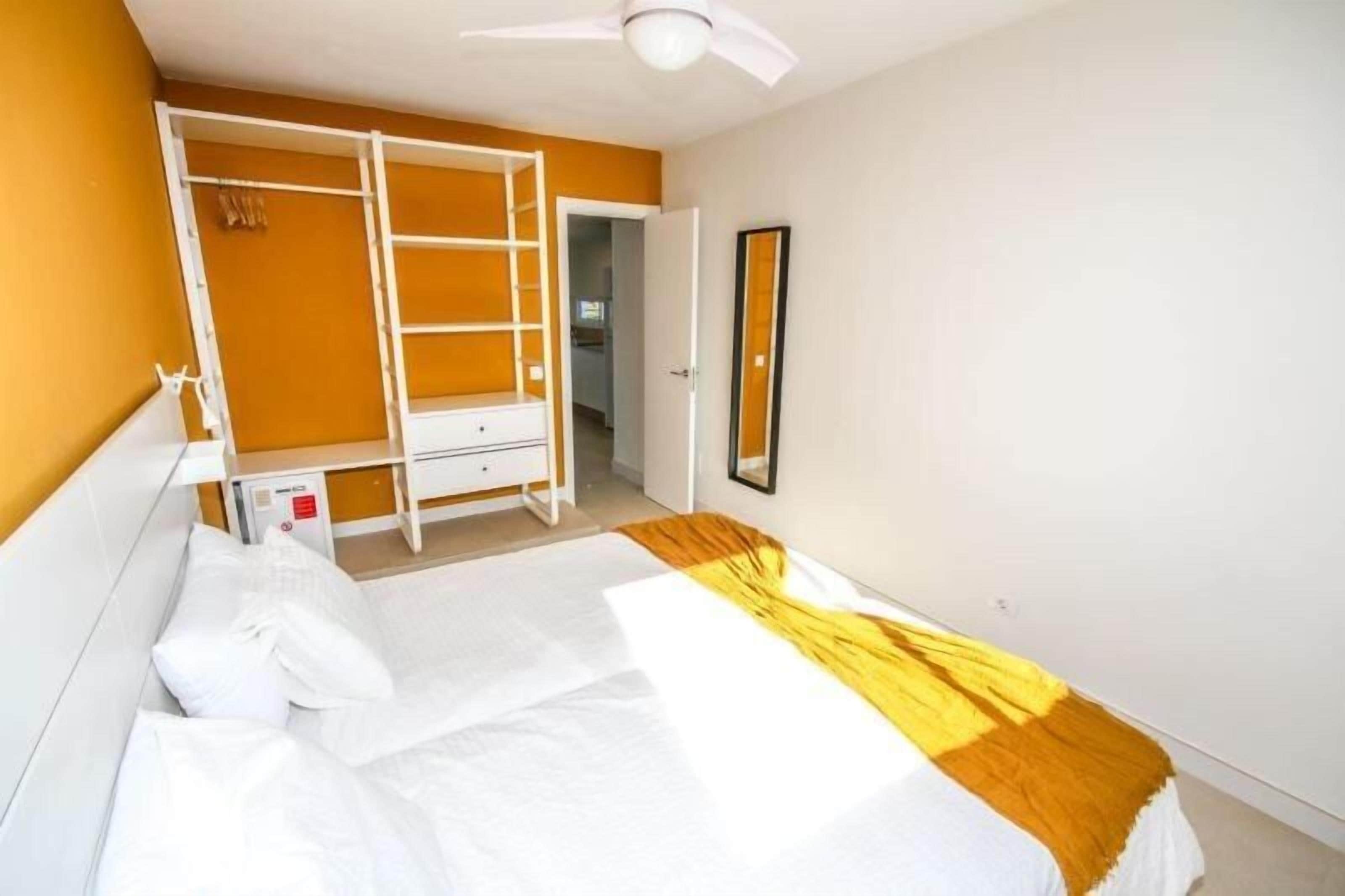 A bedroom with a bunk bed, a wardrobe, a mirror, and a ceiling fan.