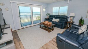 Ein Wohnzimmer mit einer Couch, einem Couchtisch und Meerblick durch große Schiebetüren.