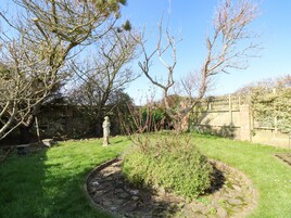 A garden with a statue, stone pathway, and a stone wall.