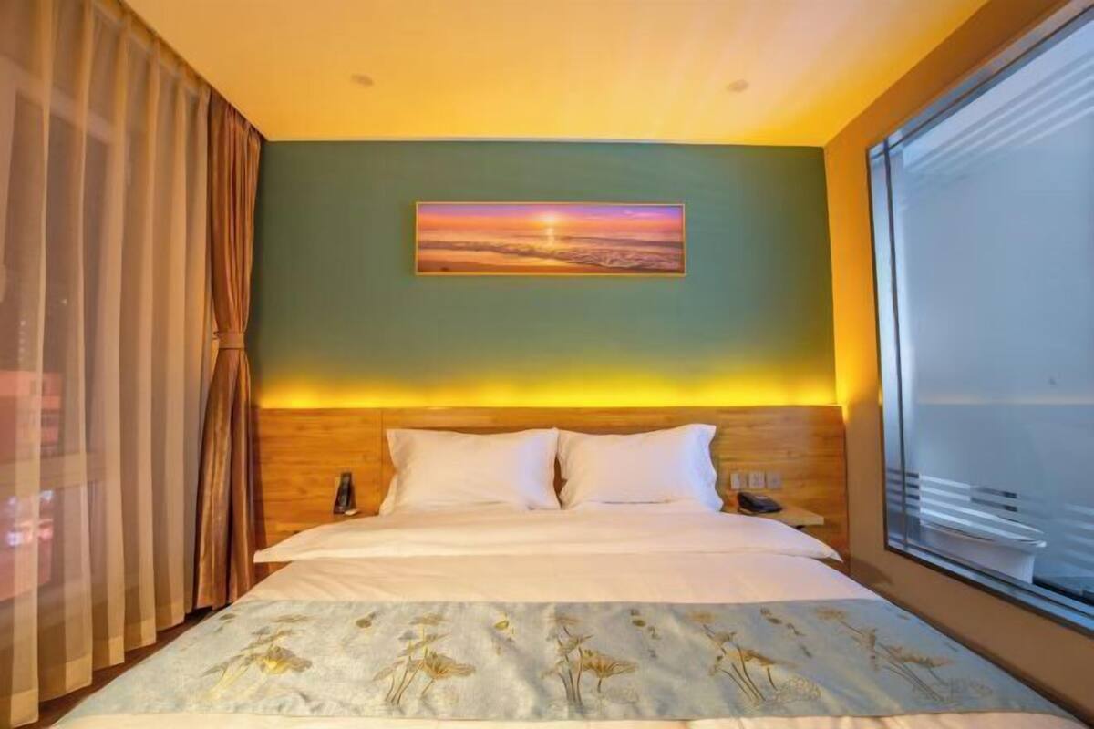 Quarto de hotel com cama, um quadro na parede e uma janela.