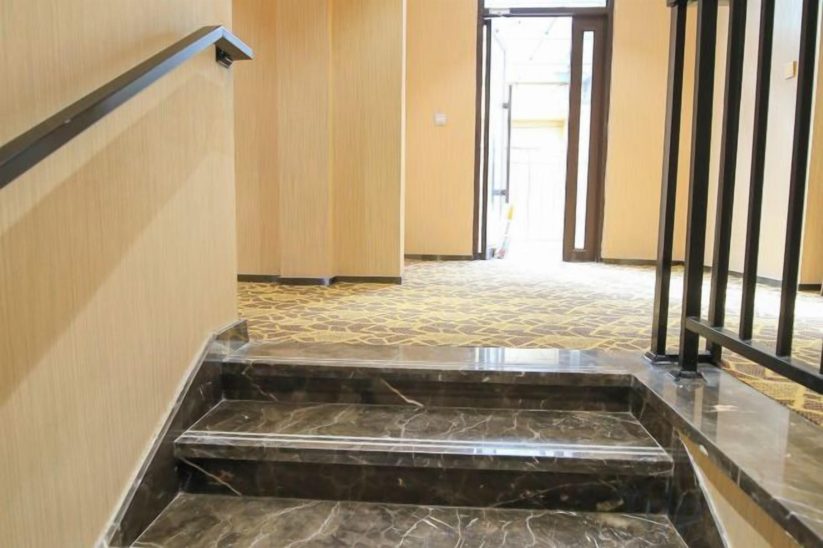Una escalera de mármol que conduce a una puerta con barandilla de metal.