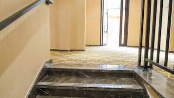 Una escalera de mármol que conduce a una puerta con barandilla de metal.