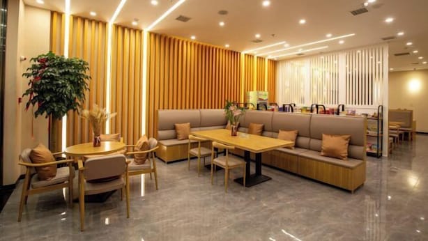 A modern hotel lobby with a seating area, a dining table, and a large plant. - Wanxi Tiantian Hotel (Shenyang)
