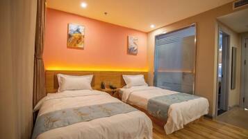Una habitación de hotel con dos camas, cabecera de madera y un ventanal grande.
