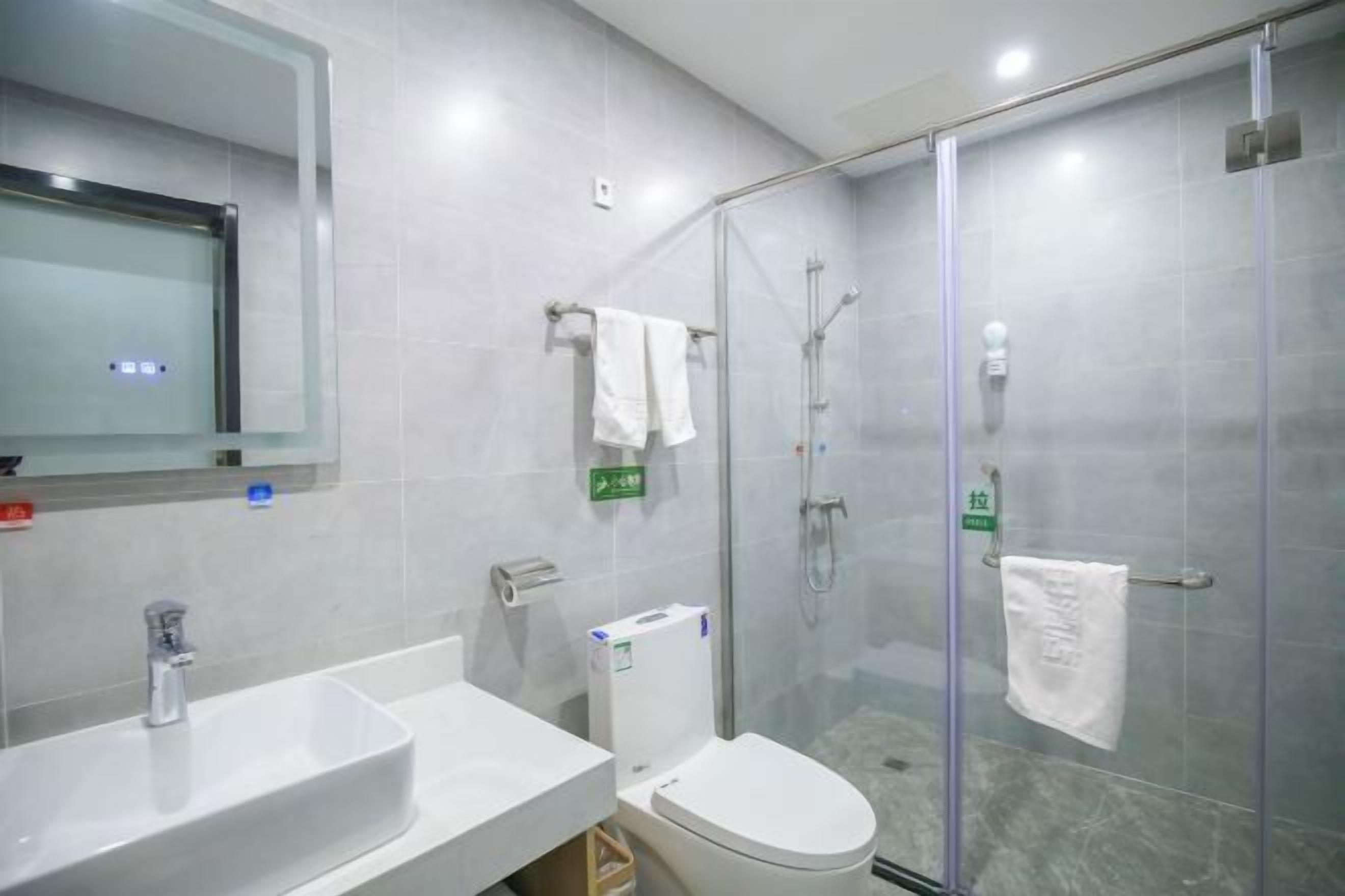 Ein modernes Badezimmer mit Duschkabine aus Glas, einem weißen Waschbecken und einer Toilette.