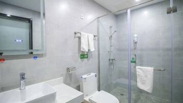 Ein modernes Badezimmer mit Duschkabine aus Glas, einem weißen Waschbecken und einer Toilette.