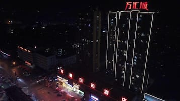 A high-rise building with illuminated signage and a parking lot.