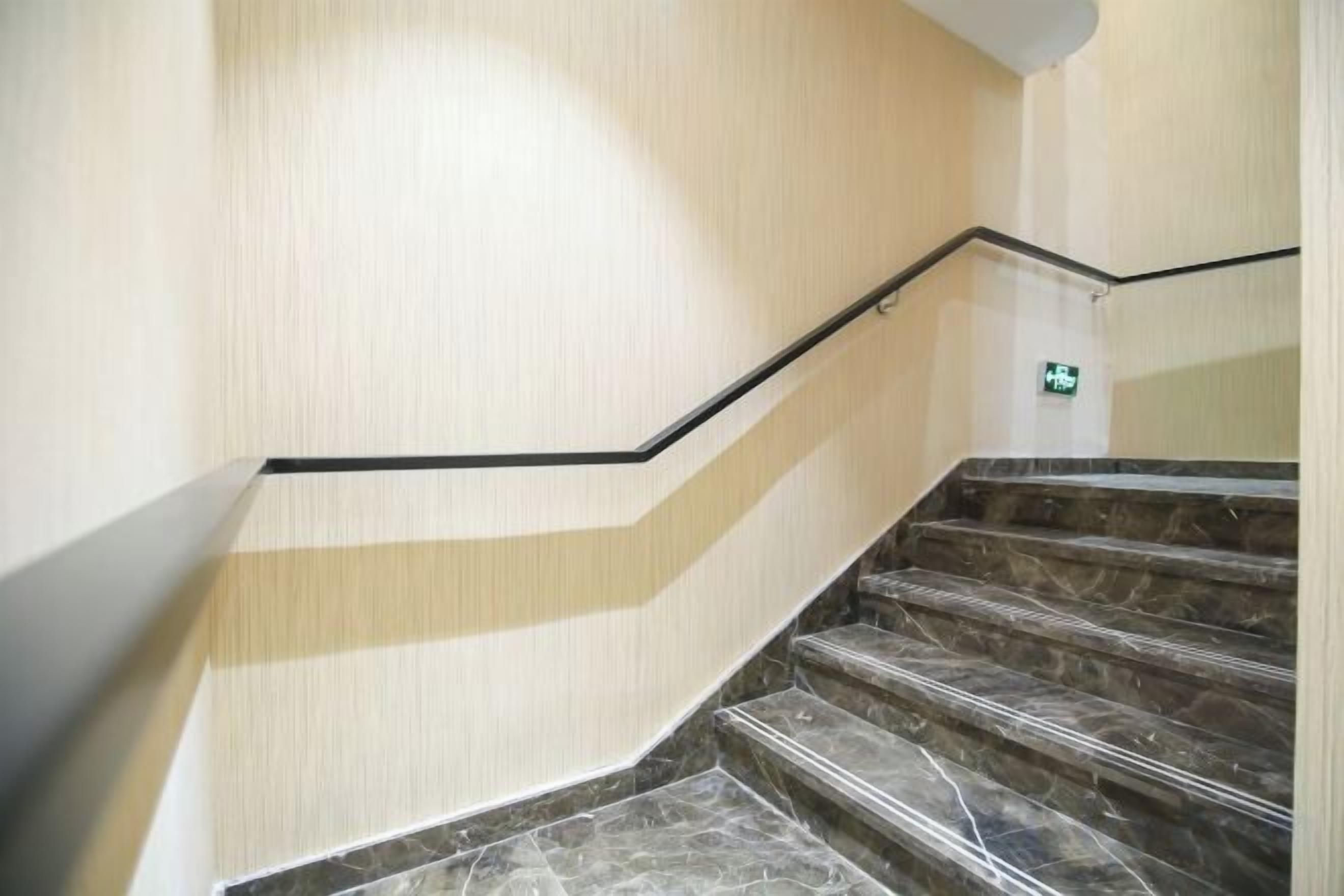 Una escalera con barandilla negra y escalones de mármol.