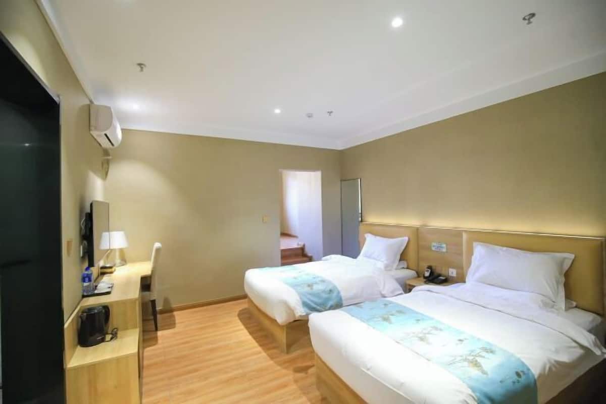 Quarto de hotel com duas camas, uma escrivaninha, uma cadeira, uma cafeteira e uma televisão.