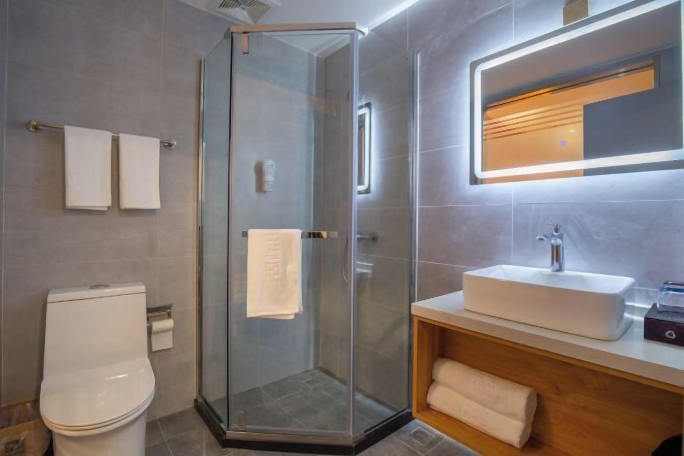 A modern bathroom with a glass-enclosed shower, a white sink, and a wooden vanity.