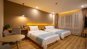 A hotel room with two beds, a wooden floor, a small round table, a desk with a lamp, and a window with sheer curtains. - Wanxi Tiantian Hotel (Shenyang)