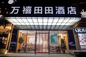 A hotel entrance with a sign, glass doors, and a seating area visible inside. - Wanxi Tiantian Hotel (Shenyang)