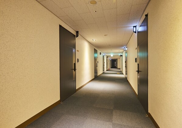A long, narrow hotel corridor with doors on both sides, leading to rooms. - Yeosu Firstcity by Sota Hotel (Yeosu)
