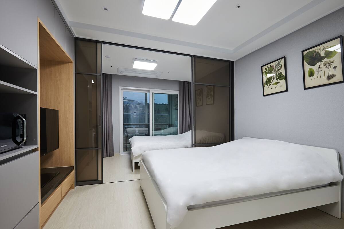 Een moderne hotelkamer met een bed, een televisie, een garderobe en een schuifdeur naar een balkon.