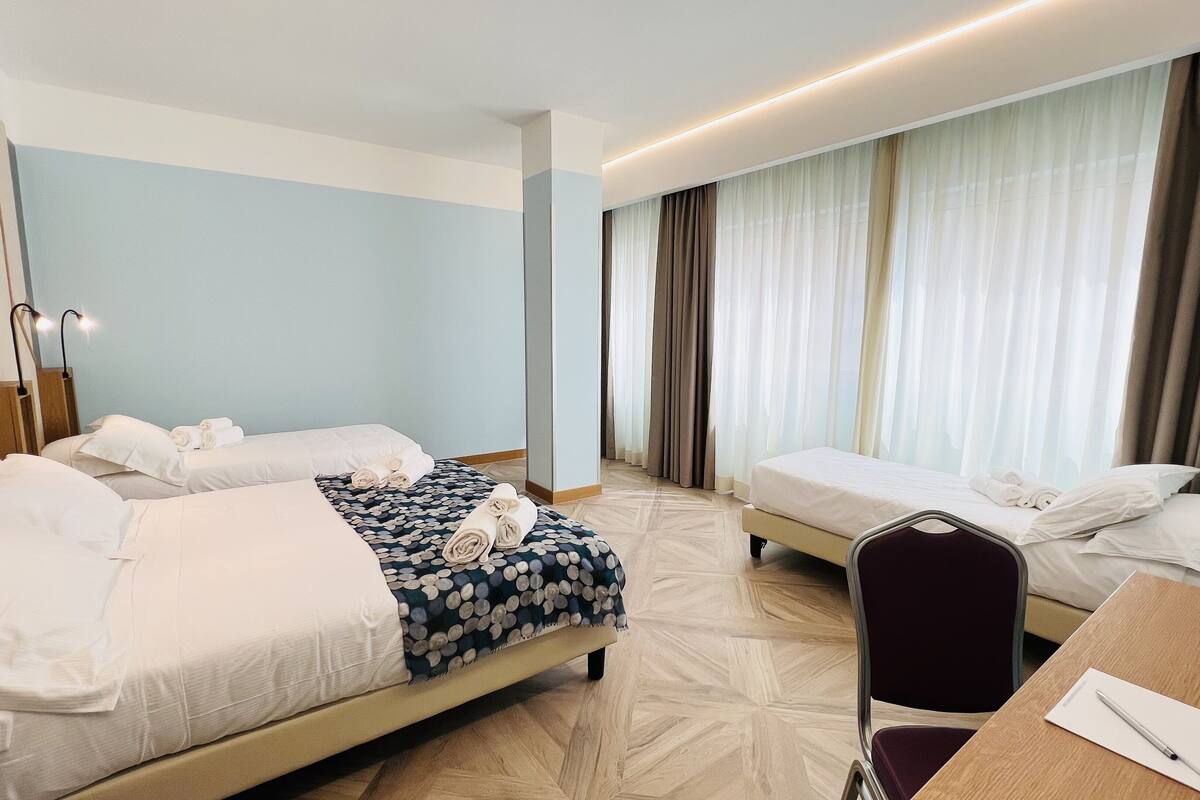 Een hotelkamer met twee bedden, een bureau en een stoel.