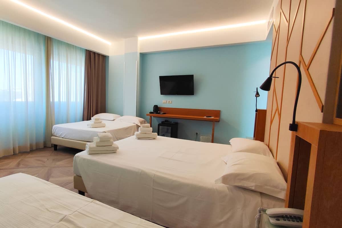 Een hotelkamer met twee bedden, een flatscreen televisie, een nachtkastje en een lamp.