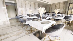 A modern dining area with marble walls and floors, featuring tables with white tablecloths and black chairs with gold legs. - Catania Sea Palace Hotel (Catania)