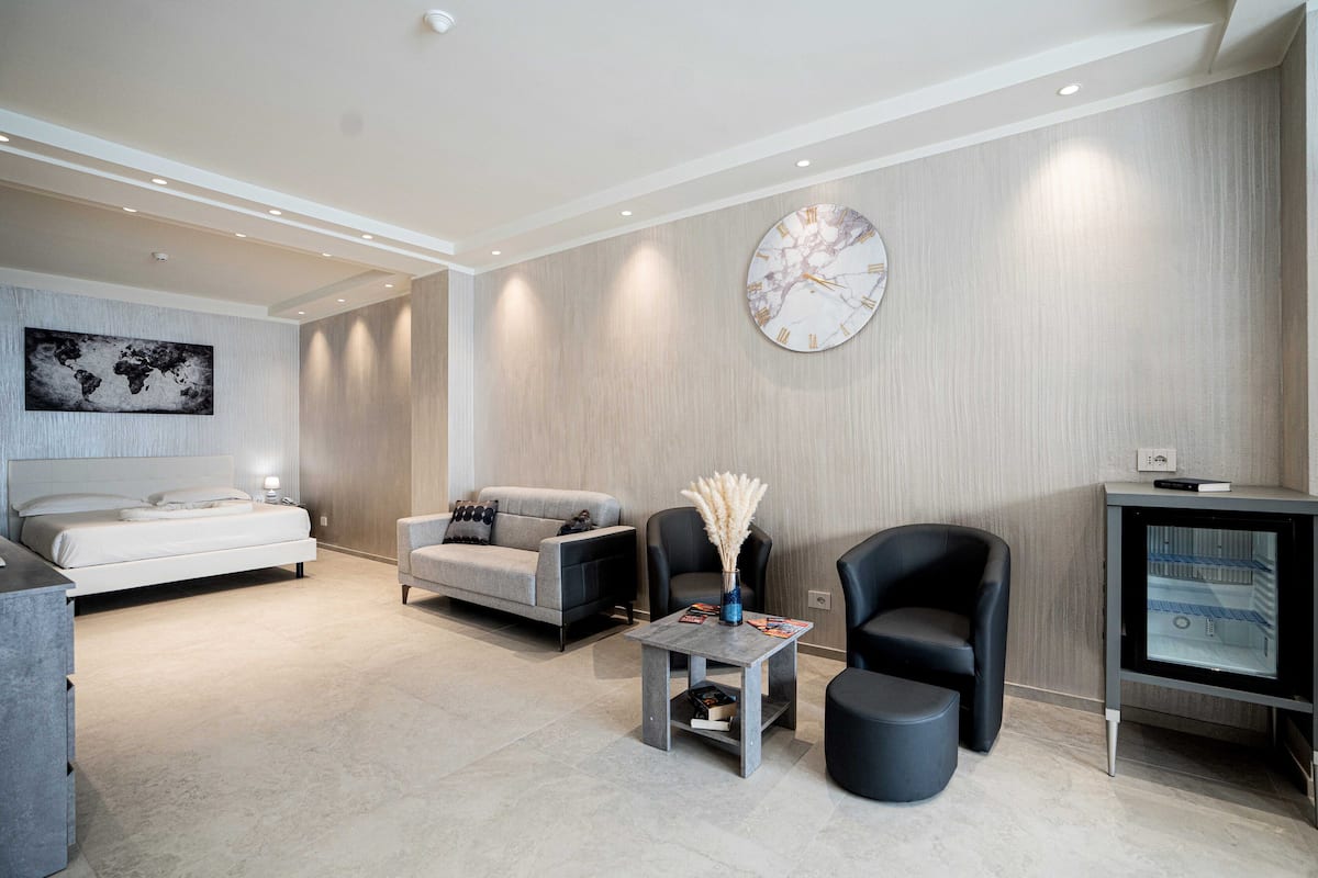 Een moderne woonkamer met een bed, bank, fauteuil, salontafel en een tv-meubel.