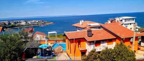 A coastal residential area with houses, a swimming pool, and a view of the sea.