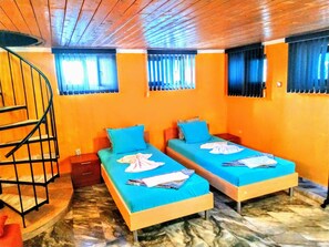 A room with two beds, a spiral staircase, and a tiled floor.
