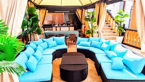 A curved sectional sofa with light blue cushions, a round coffee table, and potted plants. - All Inclusive Luxury Villa With sea View (Sozopol)