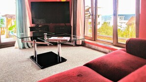 A living room with a flat-screen TV, a glass coffee table, and a red sofa. - All Inclusive Luxury Villa With sea View (Sozopol)