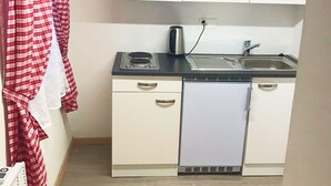 A compact kitchen with a built-in dishwasher, a kettle, and a sink. - Studio by Apartments Capricorn (Gsteigwiller)