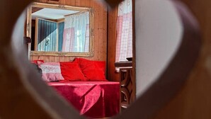 A bedroom with a wooden headboard, a mirror, and a bed with red bedding. - Studio by Apartments Capricorn (Gsteigwiller)
