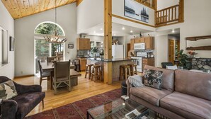 A spacious living area with a high ceiling, wooden beams, a large dining table, and a cozy seating area. - Chic Pet-Friendly Retreat | King Suite, Hot Tub | Clubhouse Access | Near Lake (Truckee)