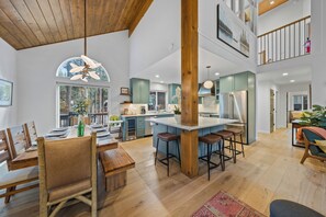 A spacious kitchen with a central island, wooden beams, and a dining area with a high chair.