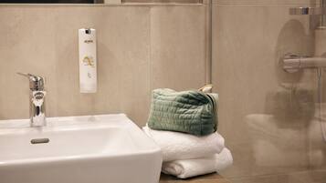 A bathroom with a white sink, a green towel, and a white bottle of lotion on the counter.