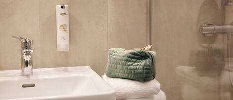 A bathroom with a white sink, a green towel, and a white bottle of lotion on the counter.