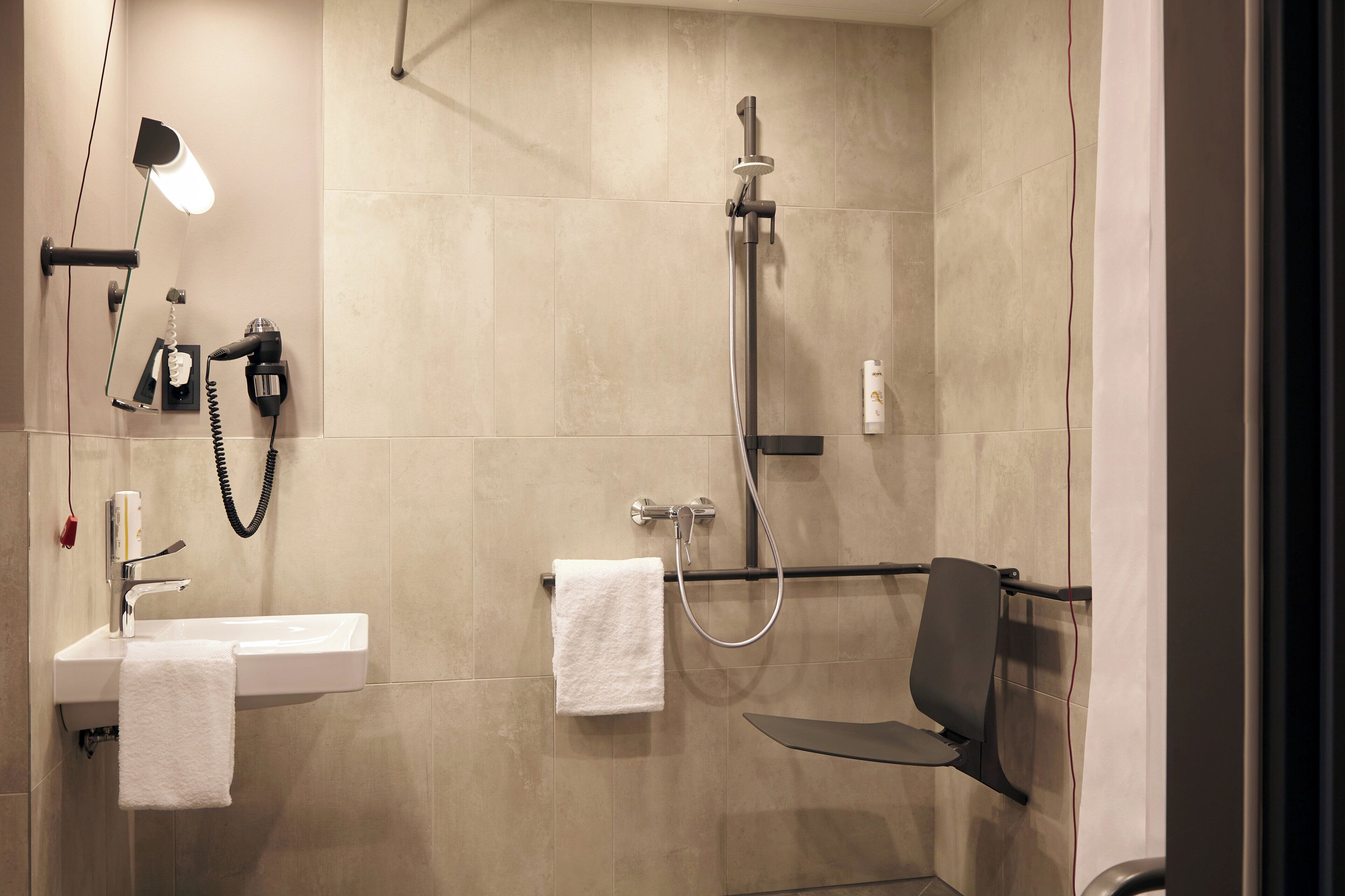 Een moderne badkamer met een wastafel, handdoekhouder en douche.